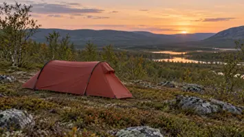 Pieni punainen sooloteltta tunturimaisemassa auringonlaskun aikaan